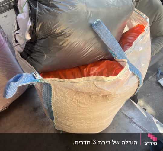 שק גדול עם בגדים על משטח הובלה